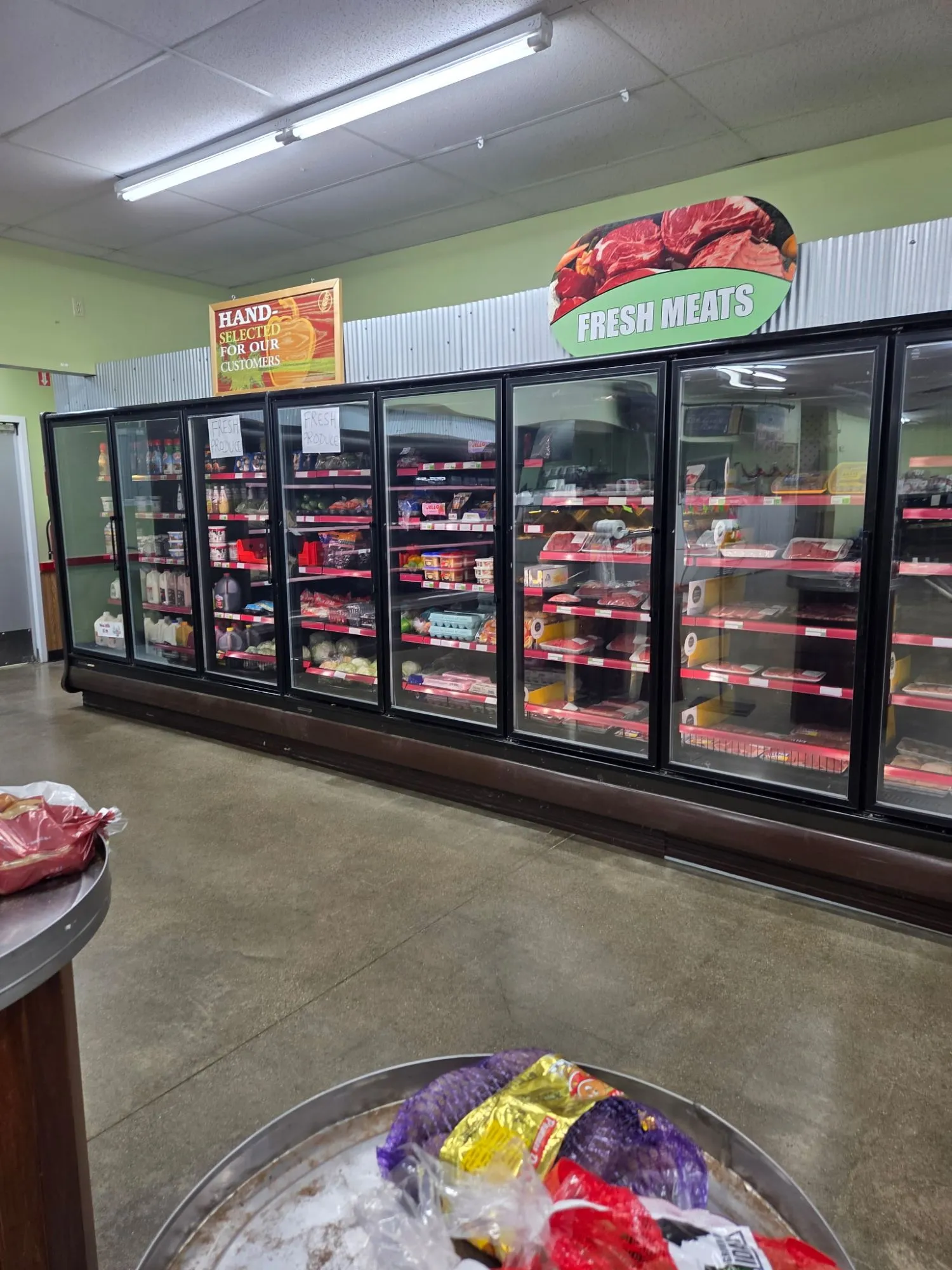 Grocery store coolers stocked with milk, produce and fresh meat