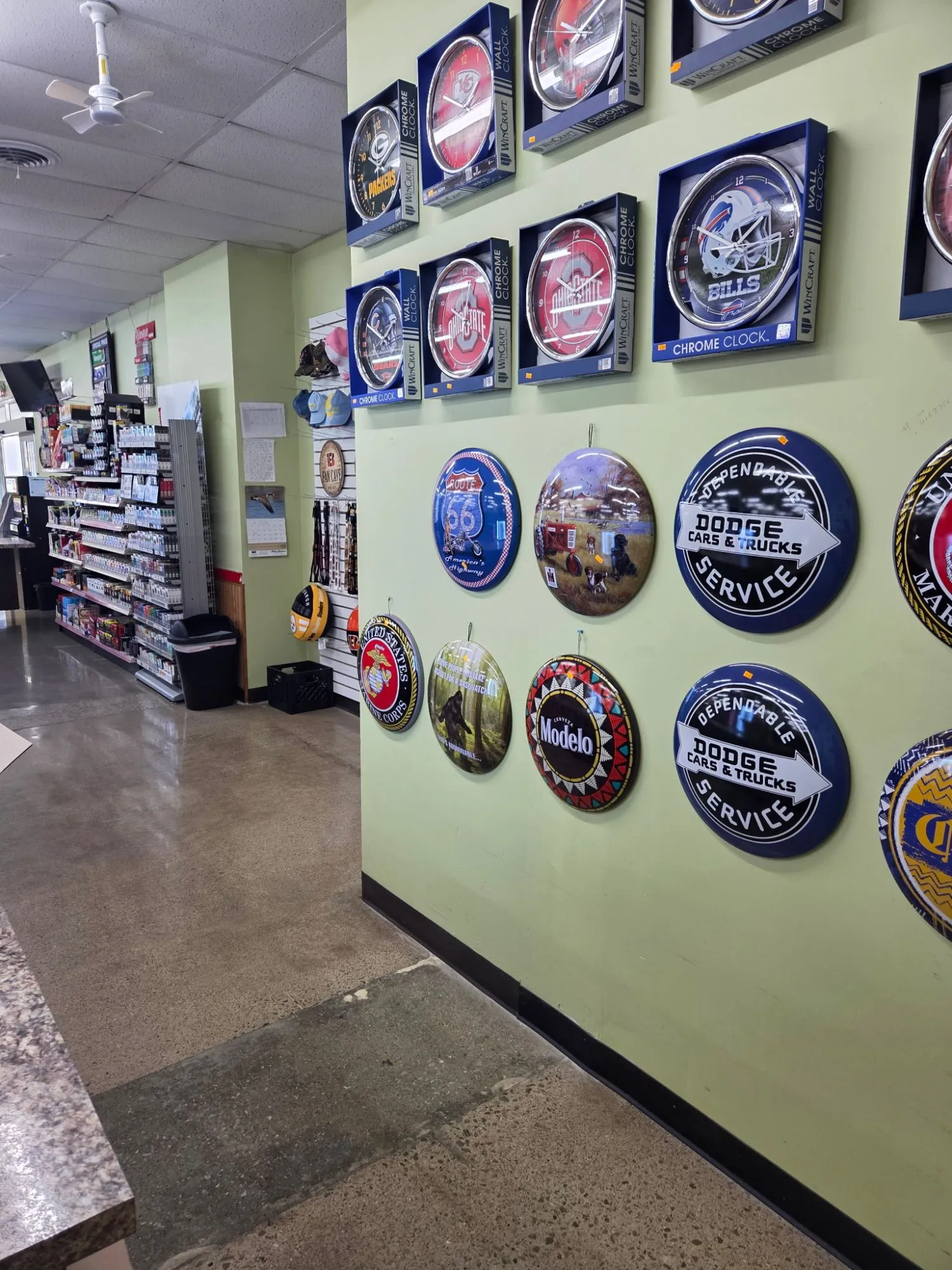 Convenience store with a tobacco aisle and a wall of signs and clocks for sale